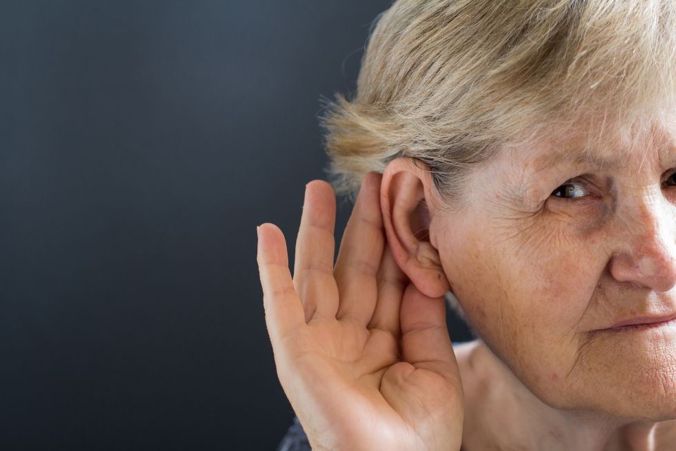 Older woman cupping her ear to hear better